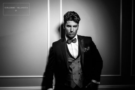 Tiendas de trajes de novio en Madrid Traje de novio semientallado negro tipo esmoquin contrastado en la solapa con tejido negro con brillo, coordinado con chaleco verde con detalles en negro y pajarita verde y negra.