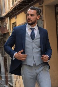 Guillermo Villanueva en las mejores tiendas de trajes de novio Chaqué corto con levita en azul noche de ojo de perdiz coordinado con pantalón y chaleco en lino de principe de gales azul con corbata en azul con lluvia blanca, trajes de novio Guillermo Villanueva España